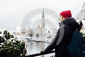 Woman in red hat enjoying the view over Hallstatt old town during snow storm, Austria