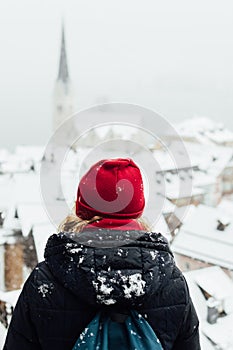 Woman in red hat enjoying the view over Hallstatt old town during snow storm, Austria