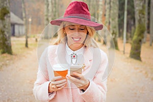 Woman with red hat looking at phone and smiling