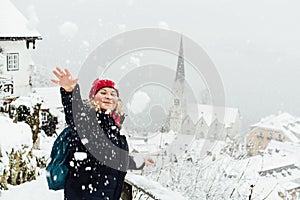 Woman in red hat playing snowballs in Hallstatt old town during snow storm, Austria