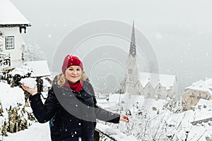 Woman in red hat playing snowballs in Hallstatt old town during snow storm, Austria