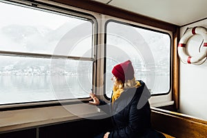 Woman in red hat sitting inside the ferry on the way to Hallstatt, Austria