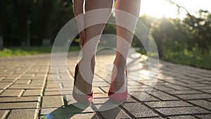 Woman in red high heels sprains foot on the street