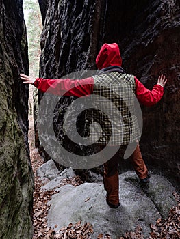 Woman with red hood walk between rocks