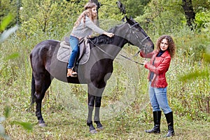 Woman in red jacket holds by bridle horse on