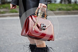 Woman with red leather bag with tiger head with gems and bamboo handle before Alberta Ferretti fashion show,
