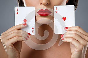 Woman with red lips is holding two aces.