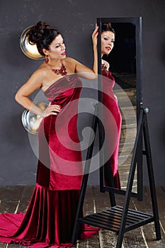 Woman in red looks away near mirror in studio with