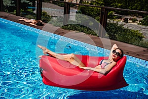 Woman on red lounger in pool