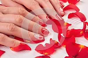 Woman red nails and rose petals.