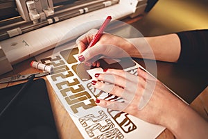 woman with red painted nails removes excess material with weeding tool to make 2022 tiger design stickers from gold vinyl foil