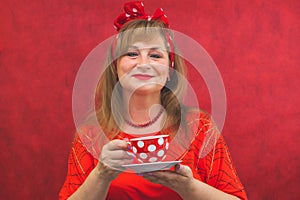 Woman in red posing on the red background. spotted cup with saucer in the hands