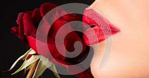 Woman with red rose, macro, on black background. Lips with lipstick closeup. Beautiful woman lips with rose.