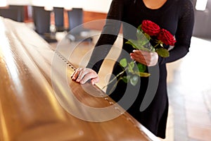 Woman with red roses and coffin at funeral