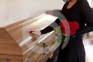 Woman with red roses and coffin at funeral