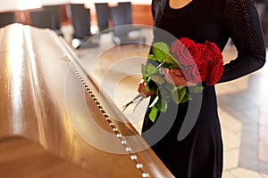 Woman with red roses and coffin at funeral