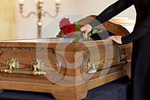 Woman with red roses and coffin at funeral
