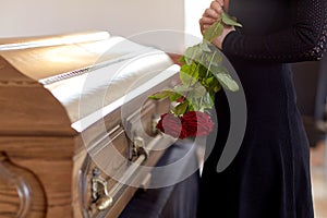 Woman with red roses and coffin at funeral