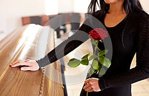 Woman with red roses and coffin at funeral