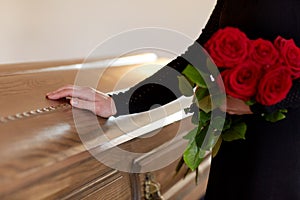 Woman with red roses and coffin at funeral