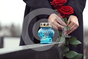 Woman with red roses, focus on candle. Funeral ceremony