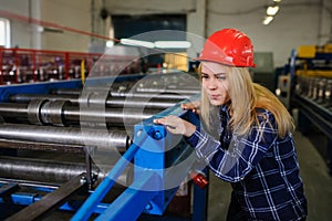 Woman in red safety helmet at metal tile roof manufacturing fact
