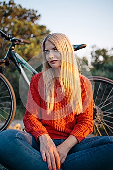 Woman in red sweater, blue jeans and yellow boots on the background of bike and forest