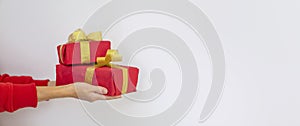 A woman in a red sweater holds a red Christmas present on a white background. Gift concept for Christmas and New Year