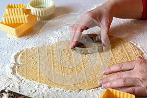 Woman in red sweater and orange apron carves cookies on the dough. Concept of festive Christmas baking