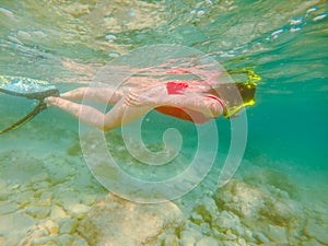 woman in red swimming suit underwater with snorkeling mask and flippers