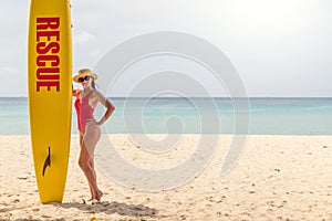 Woman in red swimsuit stand with lifeguard surf rescue board