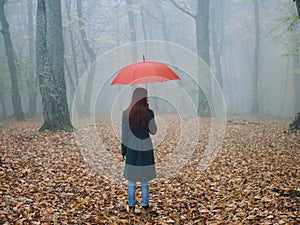 Woman with red umbrella in autumn fog yellow leaves fresh air