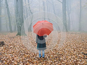 Woman with red umbrella in autumn fog yellow leaves fresh air