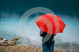 Woman with red umbrella contemplates on rain