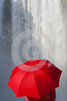 Woman With a Red Umbrella In Front Of A Waterfall