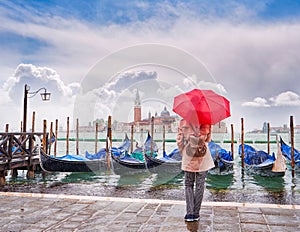 Woman with a red umbrella looking at Panoramic view of Canal Grande, Venice, Italy