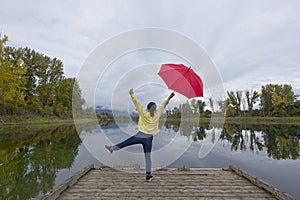 Woman with red umbrella strikes a pose on a dock