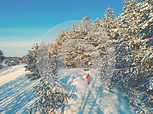 A woman in red walks along a snow-covered road