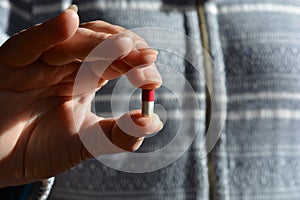 Woman with a red & white capsule in one hand