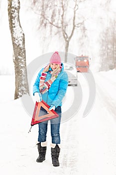 Woman with reflector triangle car snow breakdown