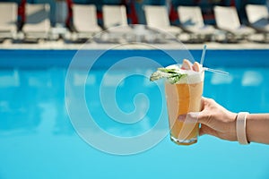 Woman with refreshing cocktail near swimming pool outdoors, closeup