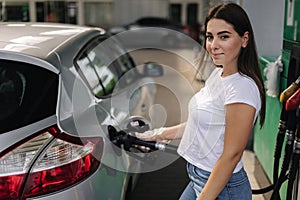 Woman is refueling at gas station. Female hand filling benzine gasoline fuel in car using a fuel nozzle. Petrol prices