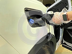 Woman refueling at gas station filling the fuel tank in a white car