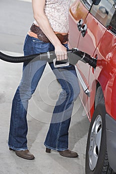 Woman Refueling Her Red Car At A Service Station