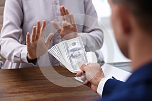 Woman refuses to take bribe money at wooden table