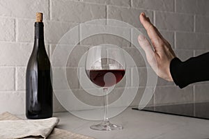 Woman refusing to drink red wine at home, closeup. Alcohol addiction treatment