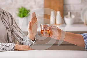 Woman refusing to drink whiskey at home. Concept of alcoholism