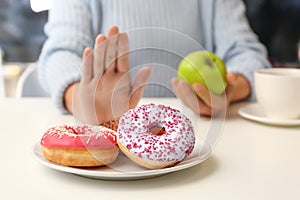 Woman refusing to eat donuts and choosing apple instead. Diabetes concept