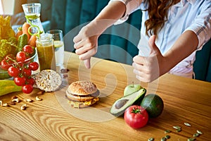 Woman is refusing to eat unhealthy hamburger. Cheap junk food vs healthy diet