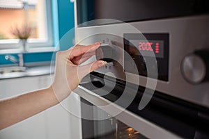 Woman regulates the temperature of the oven